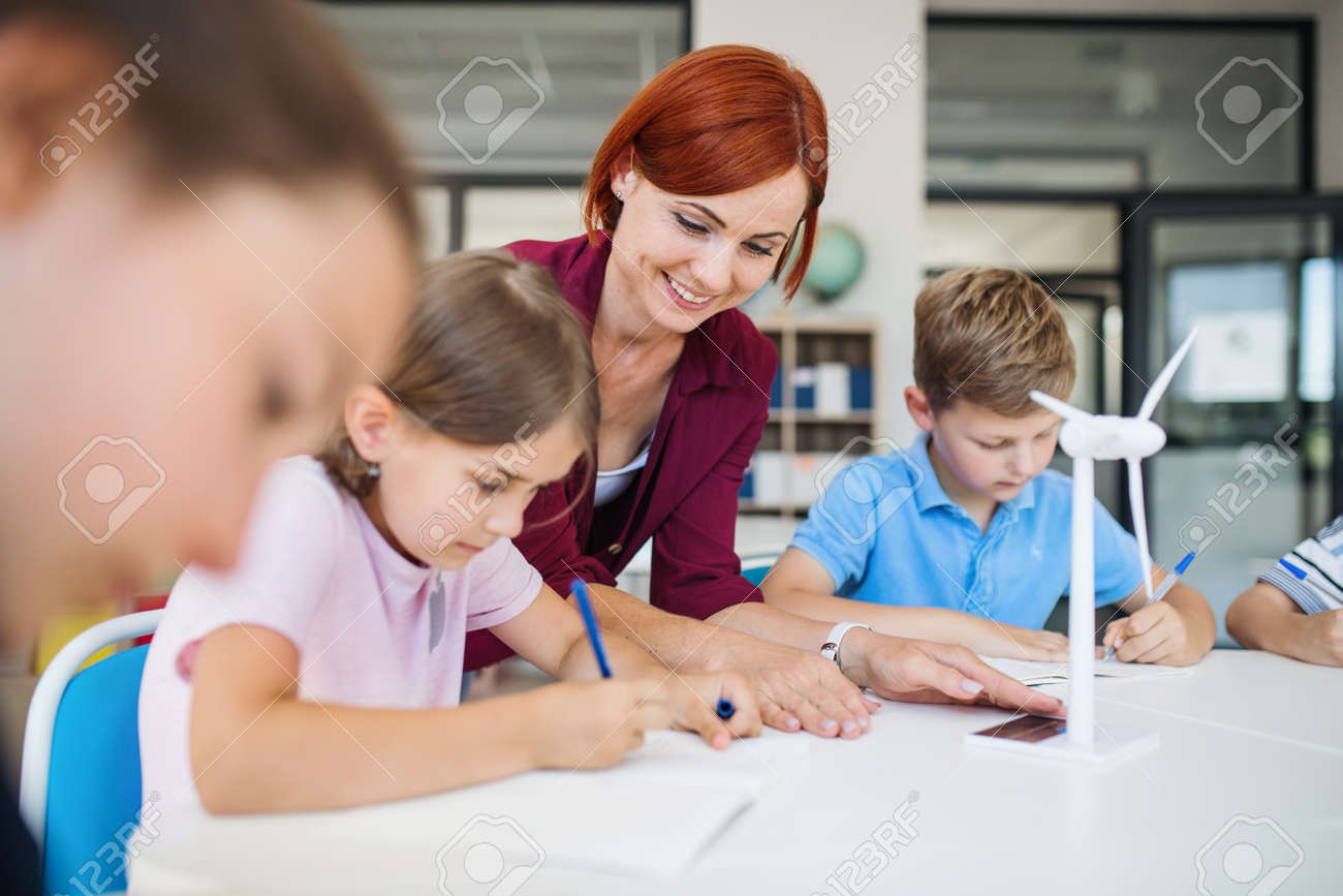 A group of small school kids with teacher in class learning about environment. - 129017447 A group of small school kids with teacher in class learning about environment. - 129017447