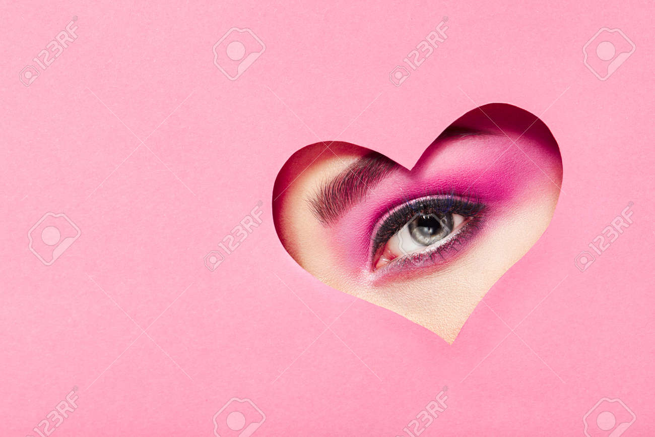 Conceptual photo of Valentine's day. Eye of Girl with Festive Pink Makeup. Paper heart on a pink background. Love symbols Valentines day - 94919549 Conceptual photo of Valentine's day. Eye of Girl with Festive Pink Makeup. Paper heart on a pink background. Love symbols Valentines day - 94919549