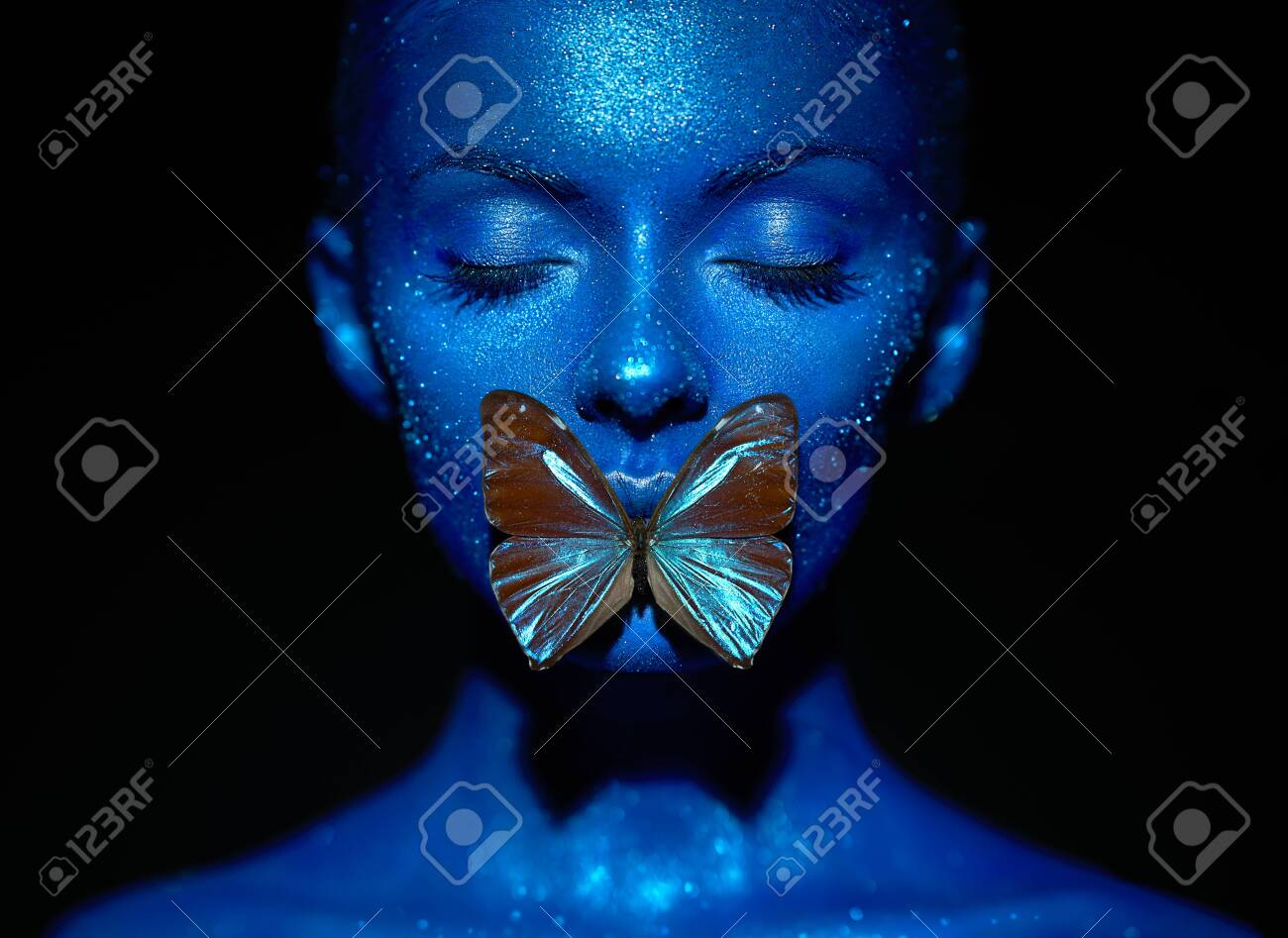 Fashion model woman in blue bright sparkles and neon lights posing in studio. Portrait of beautiful woman with blue butterfly. Art design colorful glitter glowing make up - 127785142 Fashion model woman in blue bright sparkles and neon lights posing in studio. Portrait of beautiful woman with blue butterfly. Art design colorful glitter glowing make up - 127785142