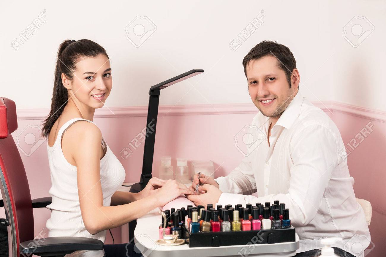 ビューティー サロンでの女性のためのマニキュアをしている男性ネイリスト の写真素材 画像素材 Image