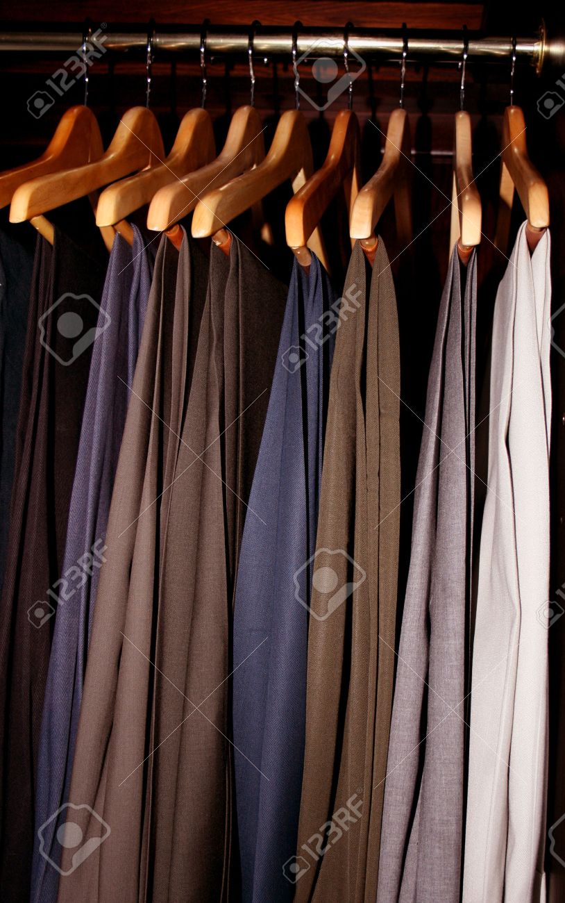 男性のドレス スラックス 暗い木製のワードローブのクローゼットにぶら下がっています の写真素材 画像素材 Image