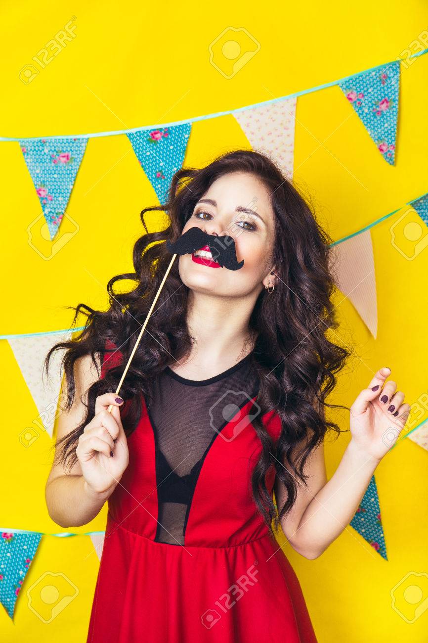 Celebracion Y Fiesta Divirtiendose Mujer Bonita Joven En Vestido Rojo Y Sombrero De Cumpleanos Se Rie Colorido Retrato De Estudio Con Fondo Amarillo La Muchacha Que Desgasta Bigotes Postizos Fotos Retratos Imagenes