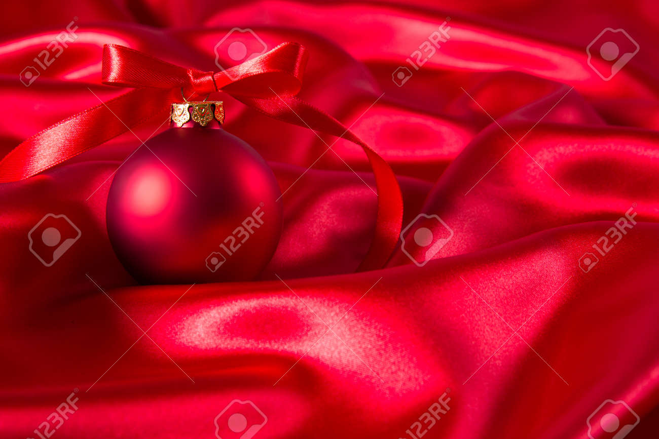 Boule De Noël Rouge Avec Un Ruban Rouge Sur Un Tissu De Soie Rouge