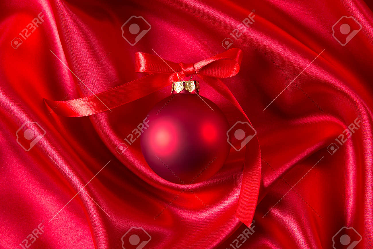 Boule De Noël Rouge Avec Un Ruban Rouge Sur Un Tissu De Soie Rouge
