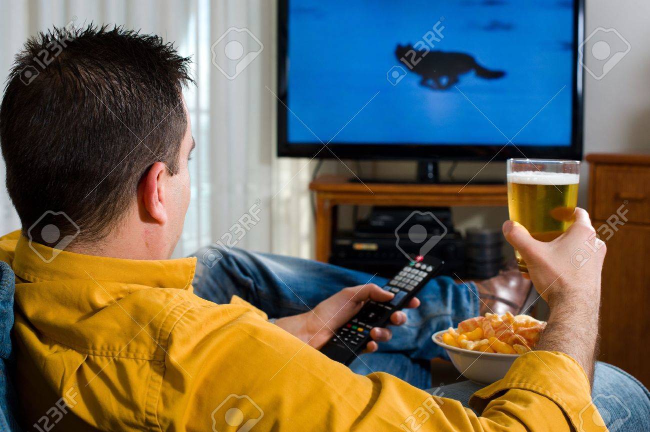 Guy enjoying his evening watching television from the sofa - 9133698 Guy enjoying his evening watching television from the sofa - 9133698