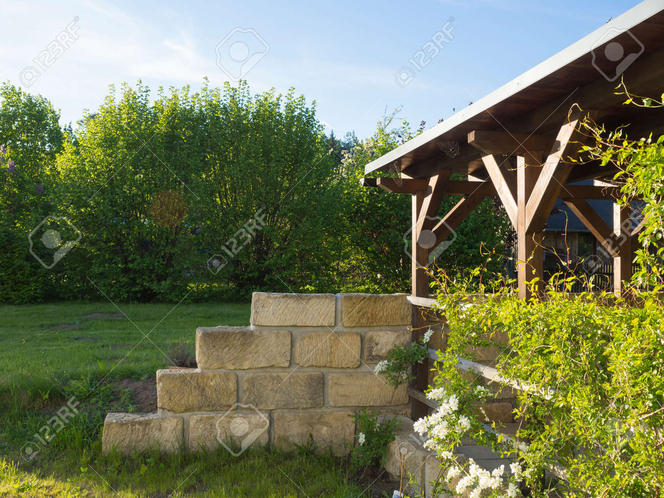 Brown Tiber Wooden Gazebo Or Pergola With Climbing Plants And brown tiber wooden gazebo or pergola with climbing plants and white flowers, surrounding sandstone wall - Brown Tiber Wooden Gazebo Or Pergola With Climbing Plants And