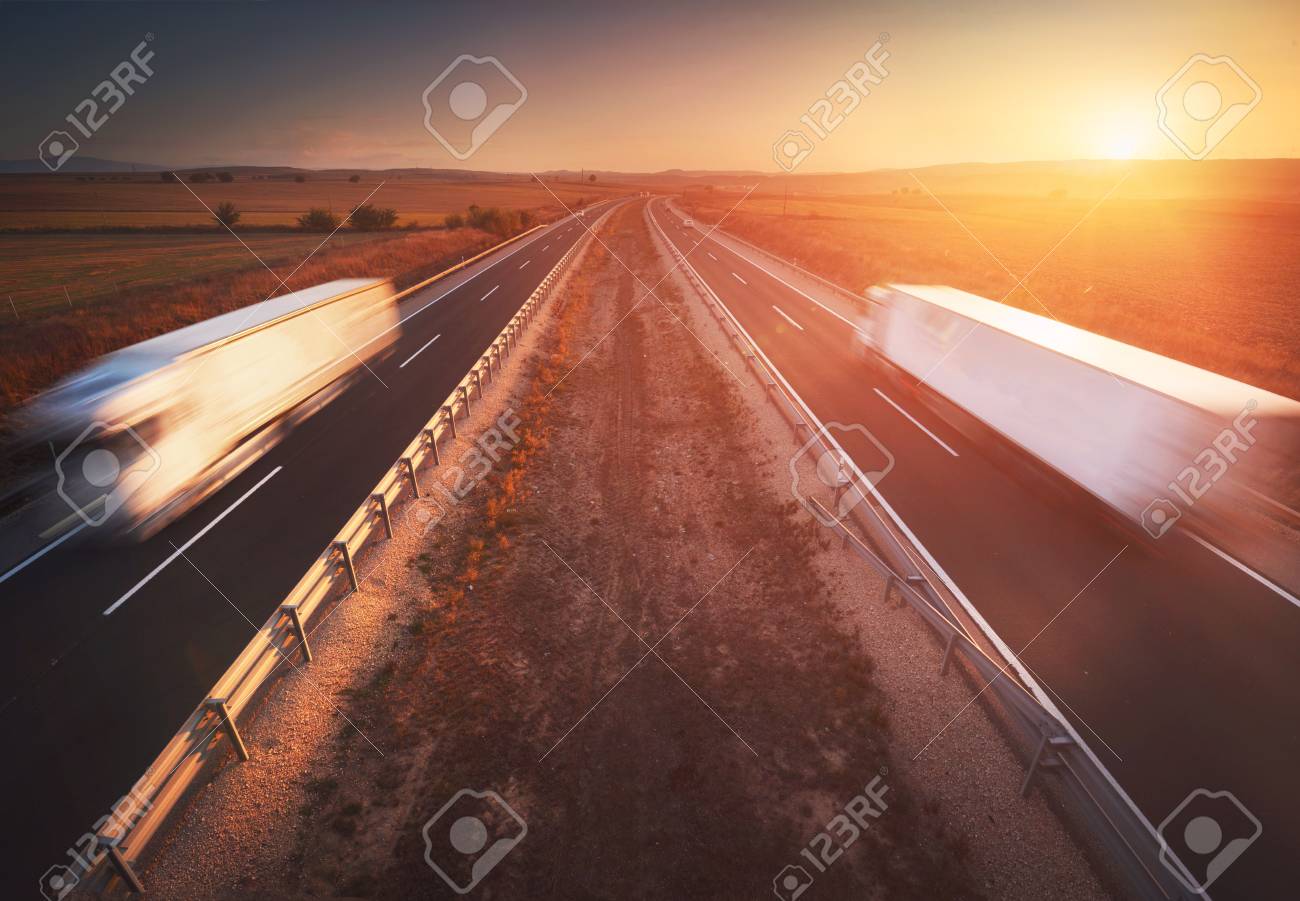 Trucks in the highway, dramatic sunset, motion blur. Cargo, transportation concept - 112674223 Trucks in the highway, dramatic sunset, motion blur. Cargo, transportation concept - 112674223