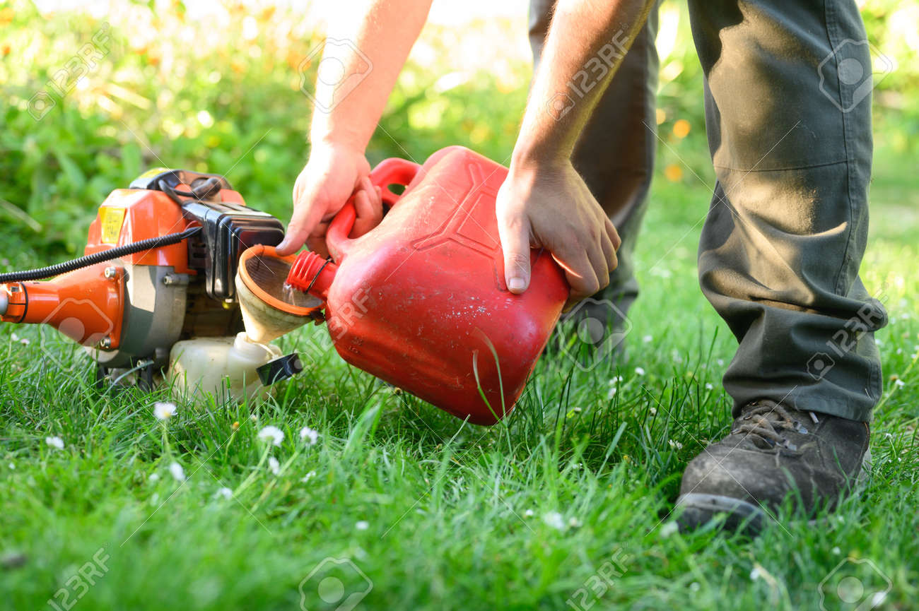 Gardener refueling brush cutter close up. Gardening tools maintenance. Lawn care with brush cutters. - 148763633 Gardener refueling brush cutter close up. Gardening tools maintenance. Lawn care with brush cutters. - 148763633