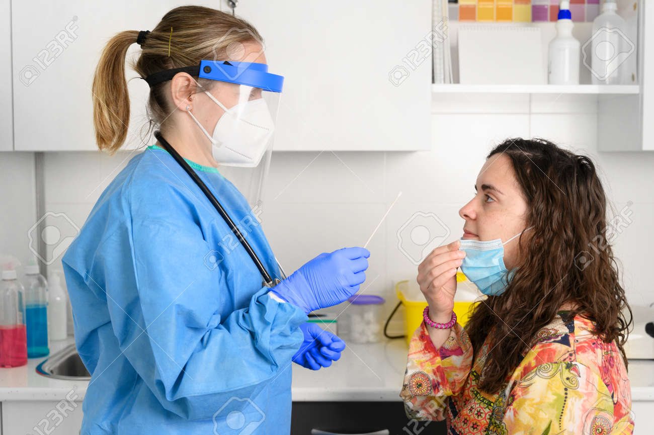Nurse in a protective suit takes a nasal swab sample from a young female patient. concept. - 167629085 Nurse in a protective suit takes a nasal swab sample from a young female patient. concept. - 167629085