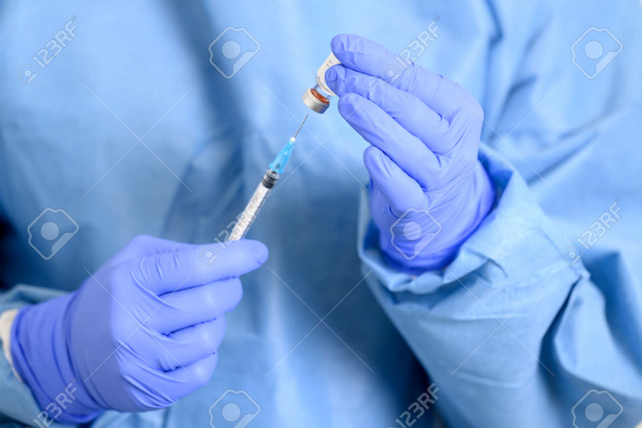 Doctor holding a syringe with a single bottle vial of vaccine. Concept fight against virus. Close up detail. Medical concept vaccination hypodermic injection treatment. - 167629231 Doctor holding a syringe with a single bottle vial of vaccine. Concept fight against virus. Close up detail. Medical concept vaccination hypodermic injection treatment. - 167629231