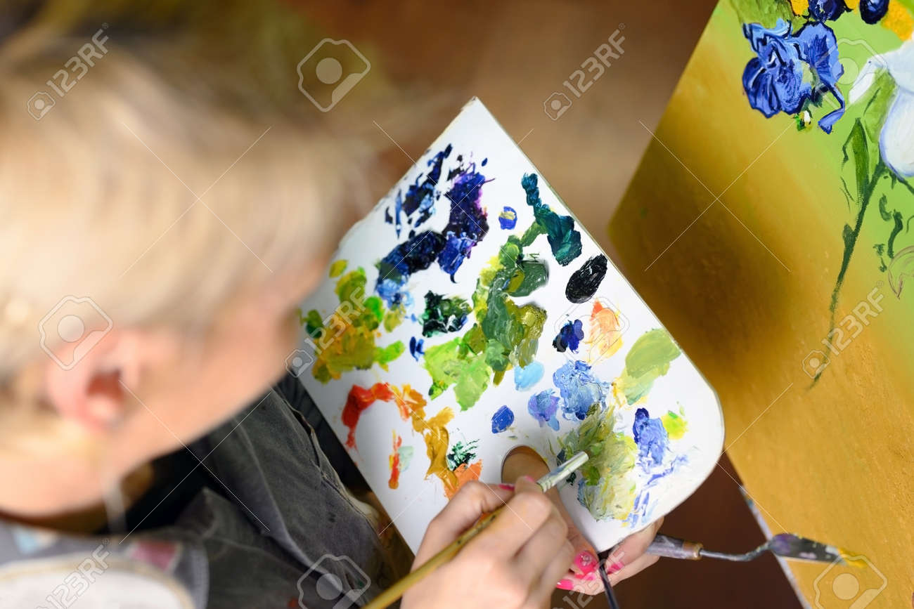 Female Artist mixes paints on the palette, painter at the studio, creator makes piece of art. - 169997528 Female Artist mixes paints on the palette, painter at the studio, creator makes piece of art. - 169997528
