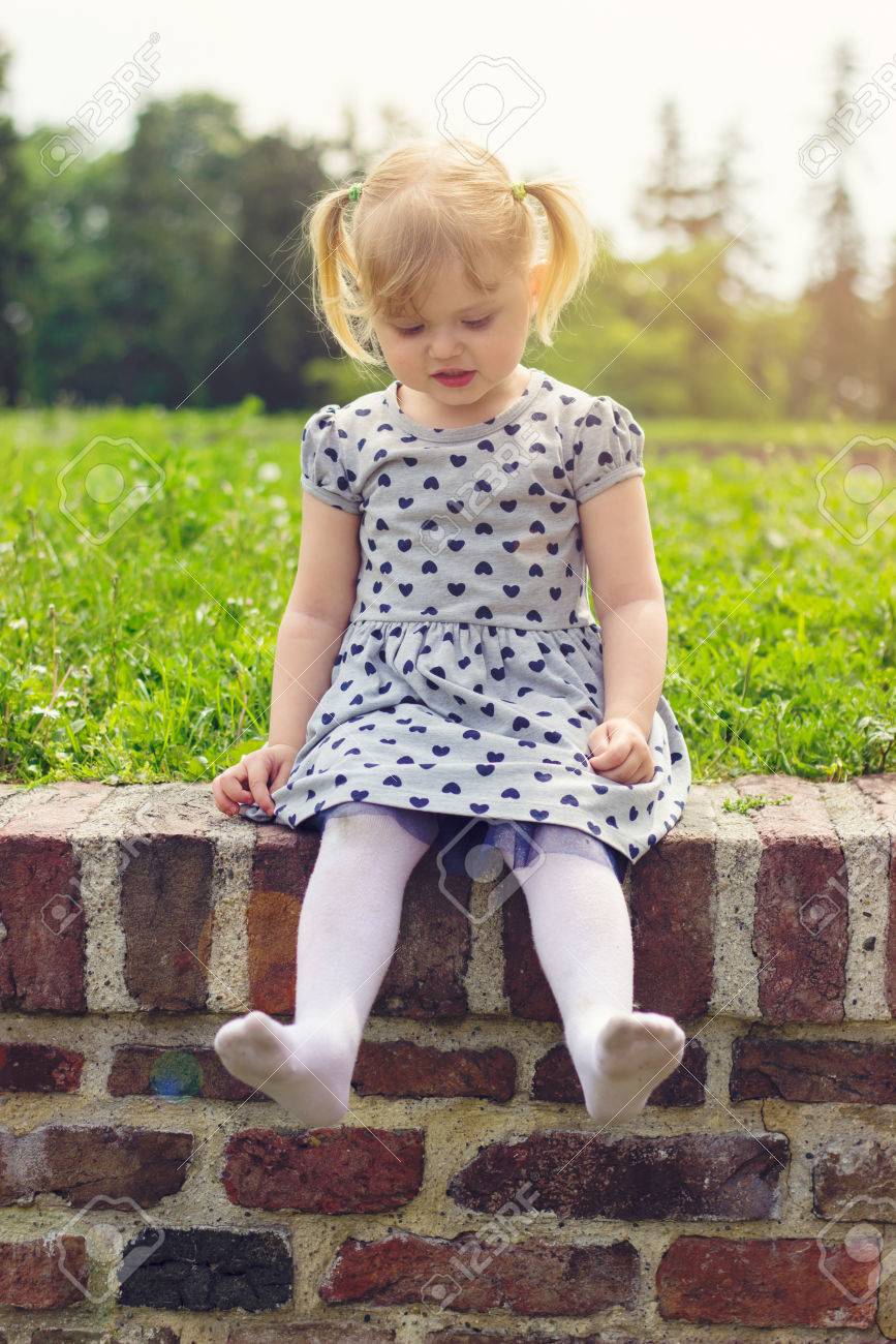 Petite Fille Assise Sur Le Mur, Heureuse D'être Pieds Nus, Elle A Enlevé  Ses Chaussures Banque D'images Et Photos Libres De Droits. Image 78707454.