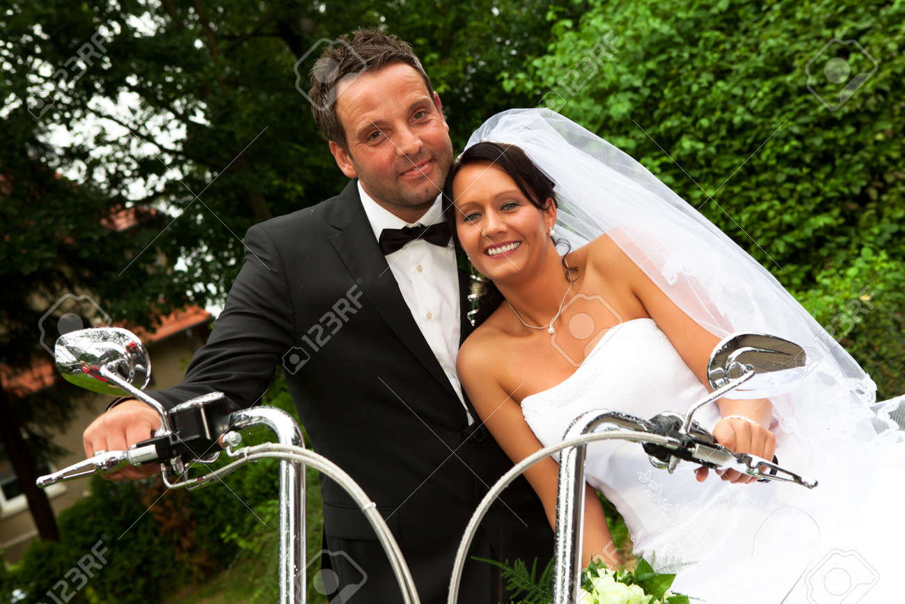 白いベールと新郎新婦蝶ネクタイでは結婚式の後バイクに座っています の写真素材 画像素材 Image