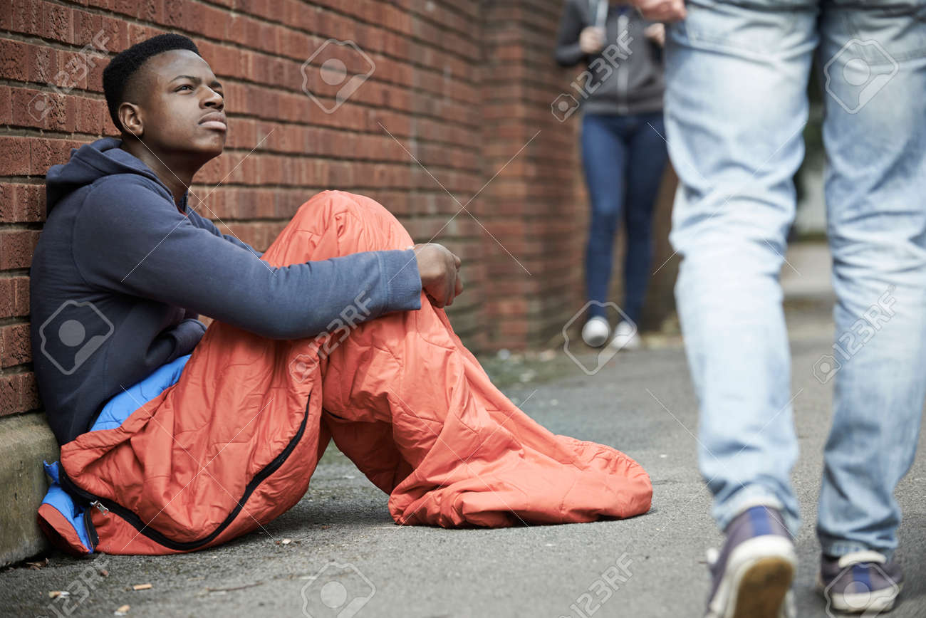 Homeless Teenage Boy In Sleeping Bag On The Street Stock Photo