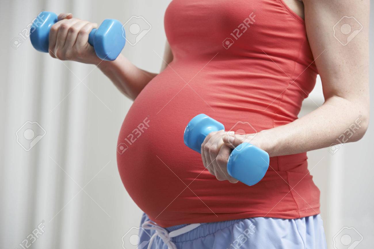 Close Up Of Pregnant Woman Exercising With Weights - 54905032 Close Up Of Pregnant Woman Exercising With Weights - 54905032