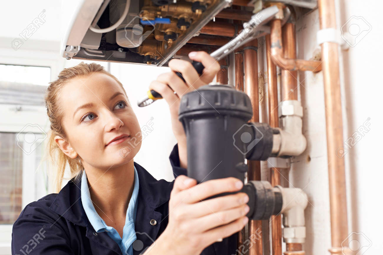 Female Plumber Working On Central Heating Boiler - 56216484 Female Plumber Working On Central Heating Boiler - 56216484