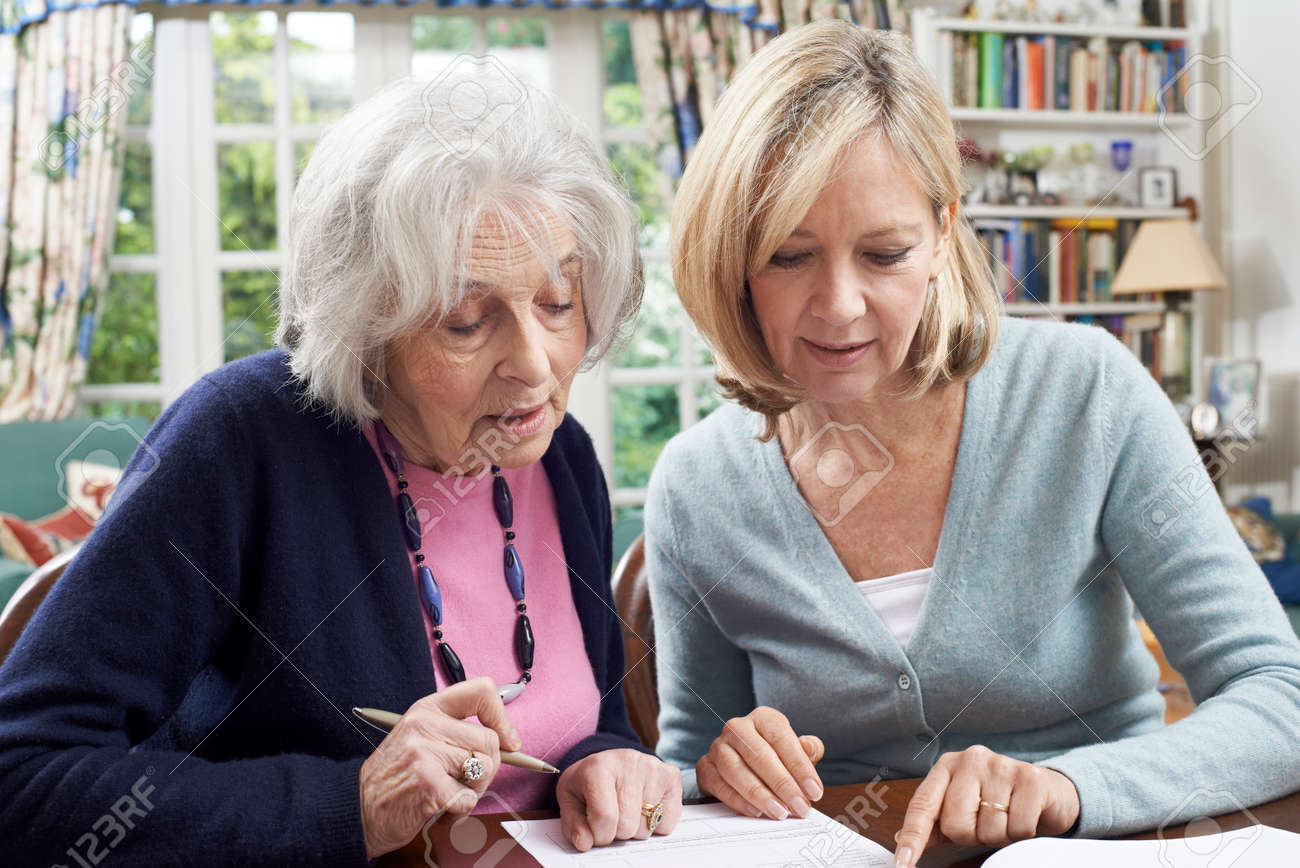 Female Neighbor Helping Senior Woman To Complete Form - 57482990 Female Neighbor Helping Senior Woman To Complete Form - 57482990
