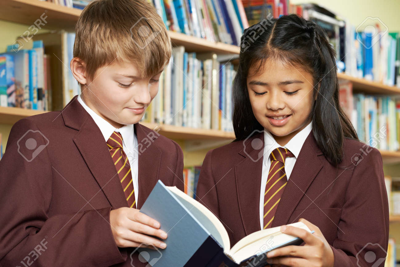 Pupils Wearing School Uniform Reading Book In Library - 63089861 Pupils Wearing School Uniform Reading Book In Library - 63089861
