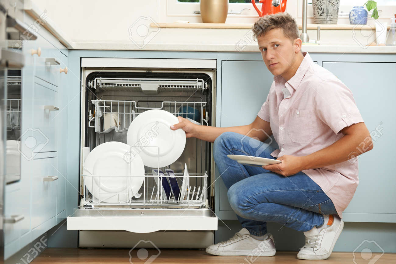 Bored Man Loading Dishwasher In Kitchen Stock Photo Bored Man Loading Dishwasher In Kitchen Stock Photo