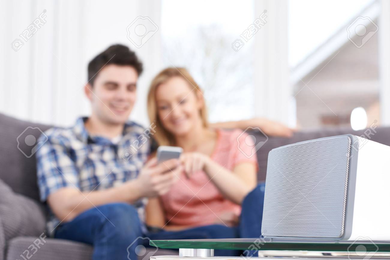 Couple Streaming Music From Mobile Phone To Wireless Speaker - 72085184 Couple Streaming Music From Mobile Phone To Wireless Speaker - 72085184