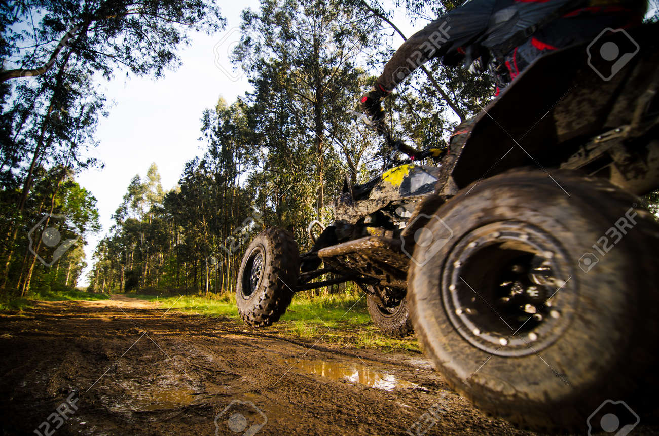 Quad rider jumping on a muddy forest trail. - 21174410 Quad rider jumping on a muddy forest trail. - 21174410