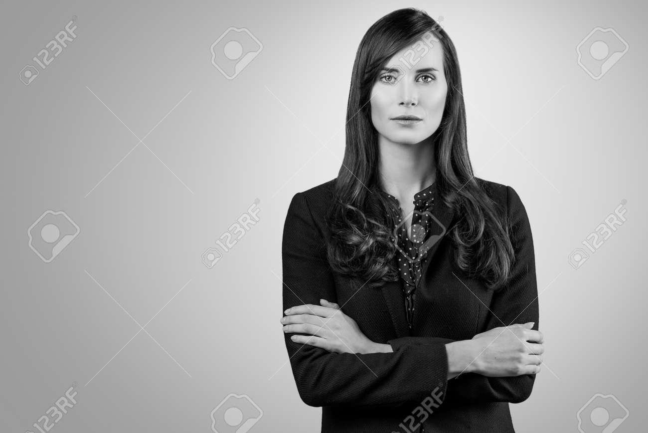 Black and white portrait of a beautiful elegant professional woman standing with folded arms in a