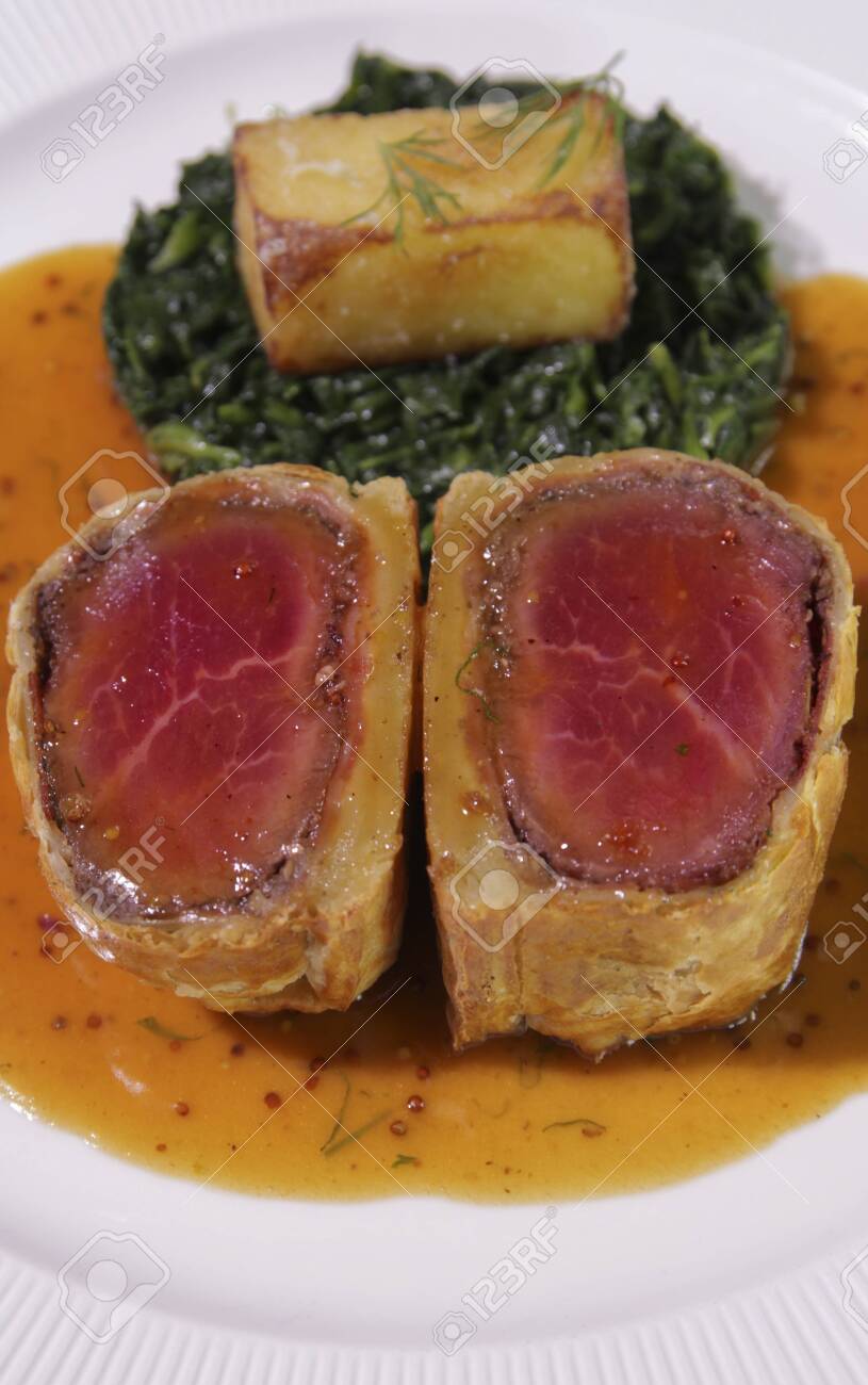 Slice of Beef Wellington with Spinach and fried potatoes. - 142631910 Slice of Beef Wellington with Spinach and fried potatoes. - 142631910