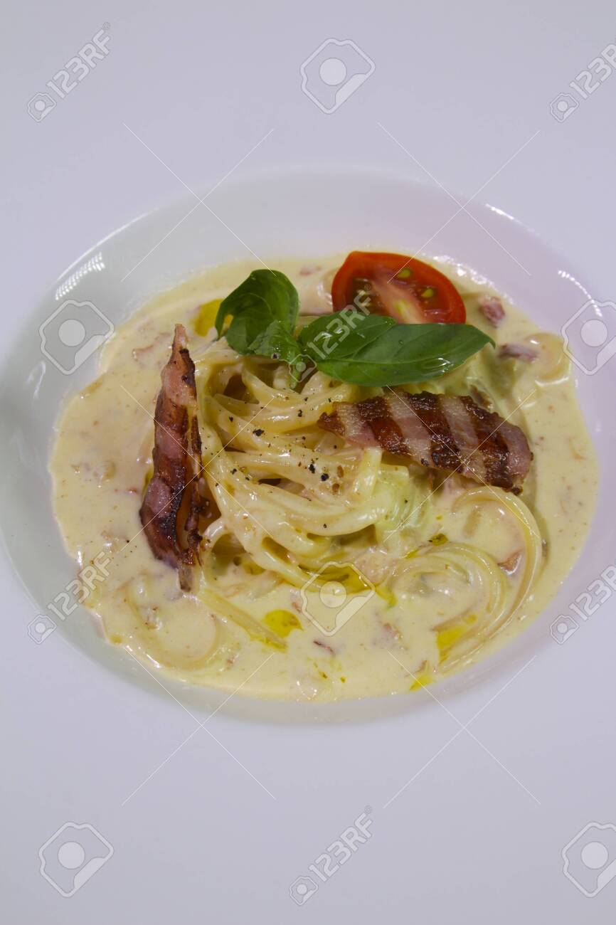 Spaghetti carbonara served with cheese, grilled bacon, cherry tomato, mint on a white plate.Close up.Copy spase. - 142921487 Spaghetti carbonara served with cheese, grilled bacon, cherry tomato, mint on a white plate.Close up.Copy spase. - 142921487