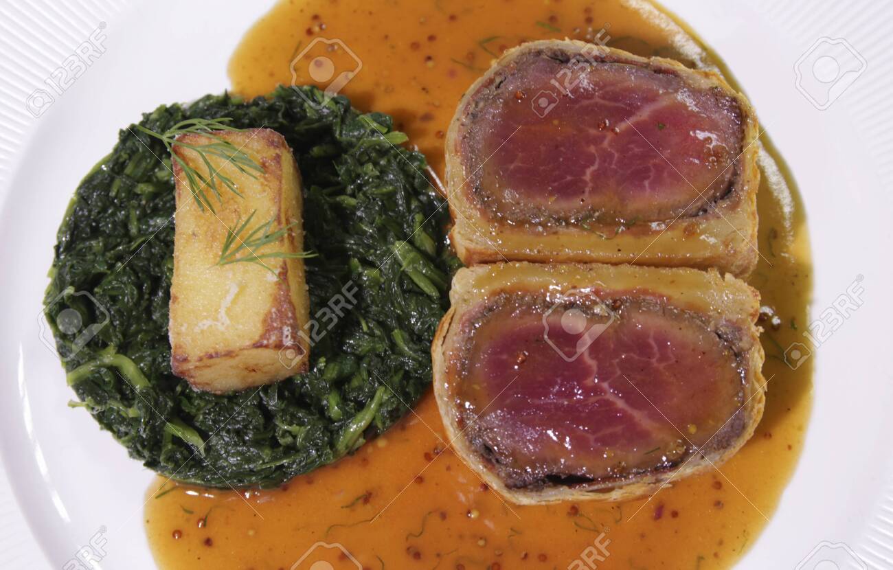 Carved Beef Wellington with Spinach and fried potatoes. - 144390485 Carved Beef Wellington with Spinach and fried potatoes. - 144390485