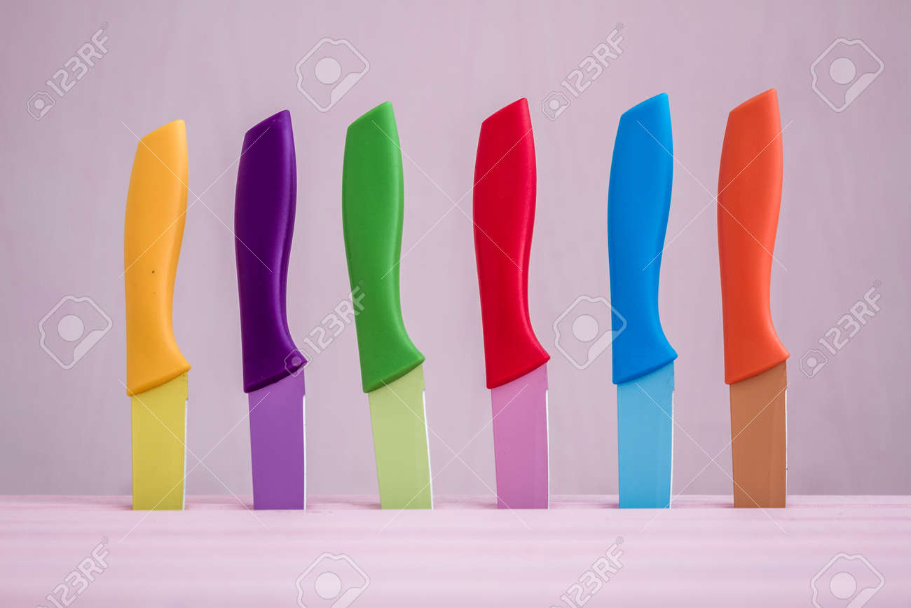 Set Of Colorful Kitchen Knives Over Pink Background Stock Photo