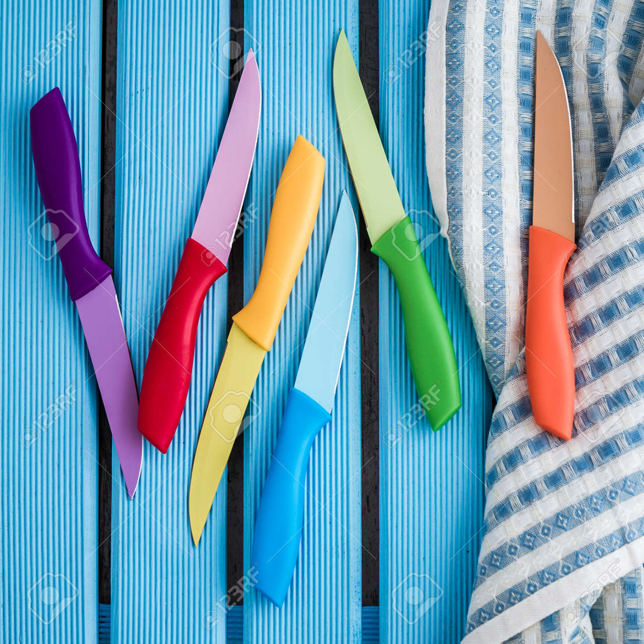 Set Of Colorful Kitchen Knives On Kitchen Napkin Stock Photo