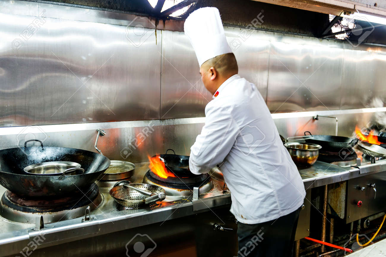 Restaurant Kitchen Chefs chef in restaurant kitchen at stove with pan, doing flambe on Restaurant Kitchen Chefs chef in restaurant kitchen at stove with pan, doing flambe on
