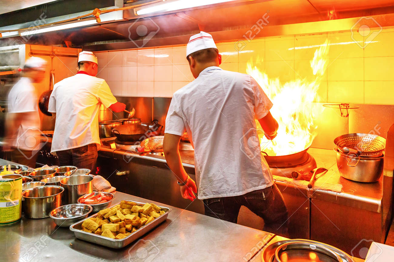 Restaurant Kitchen Chefs chef in restaurant kitchen at stove with pan, doing flambe on Restaurant Kitchen Chefs chef in restaurant kitchen at stove with pan, doing flambe on