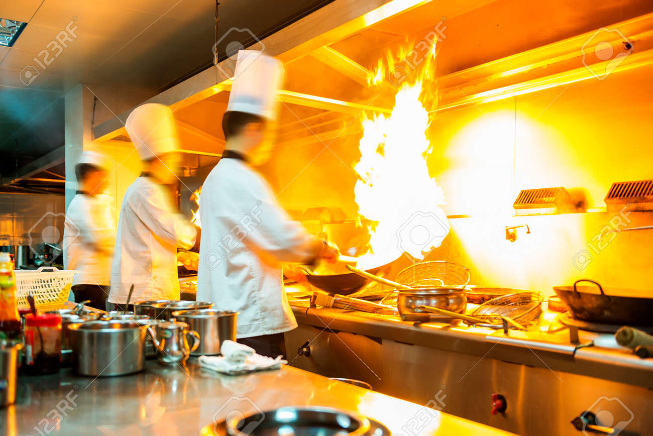 Restaurant Kitchen Chefs chef in restaurant kitchen at stove with pan, doing flambe on Restaurant Kitchen Chefs chef in restaurant kitchen at stove with pan, doing flambe on
