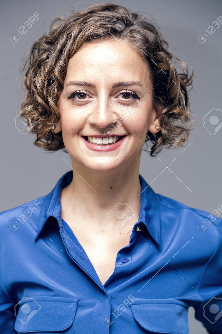 Young Woman With Short Curly Hair In Blue Blouse Studio Portrait