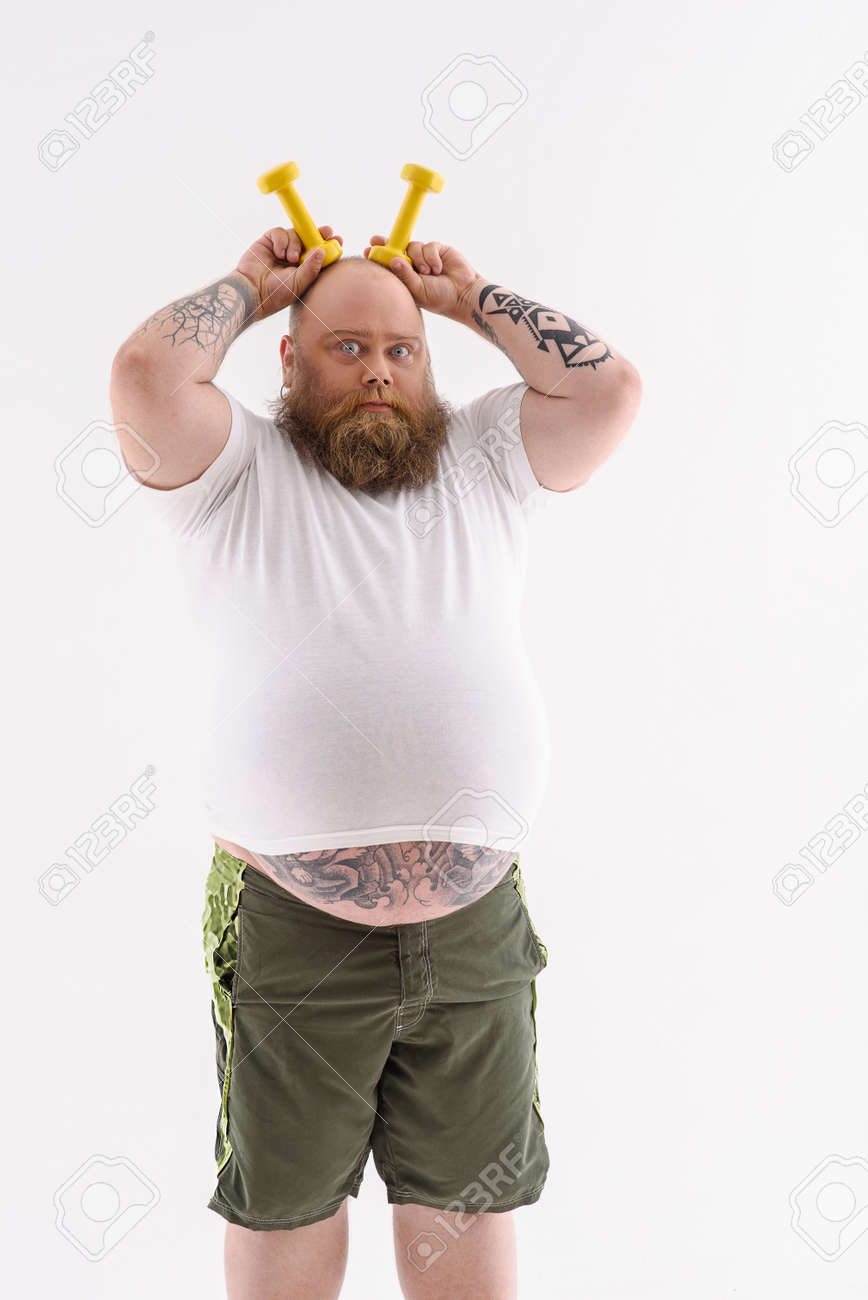 Gros Homme Barbu Tient Des Poids Près De La Tête Comme Des Oreilles. Il Est  Debout Et Regarde Avec Impatience Avec Sérieux. Isolé Banque D'Images et  Photos Libres De Droits. Image 61178511