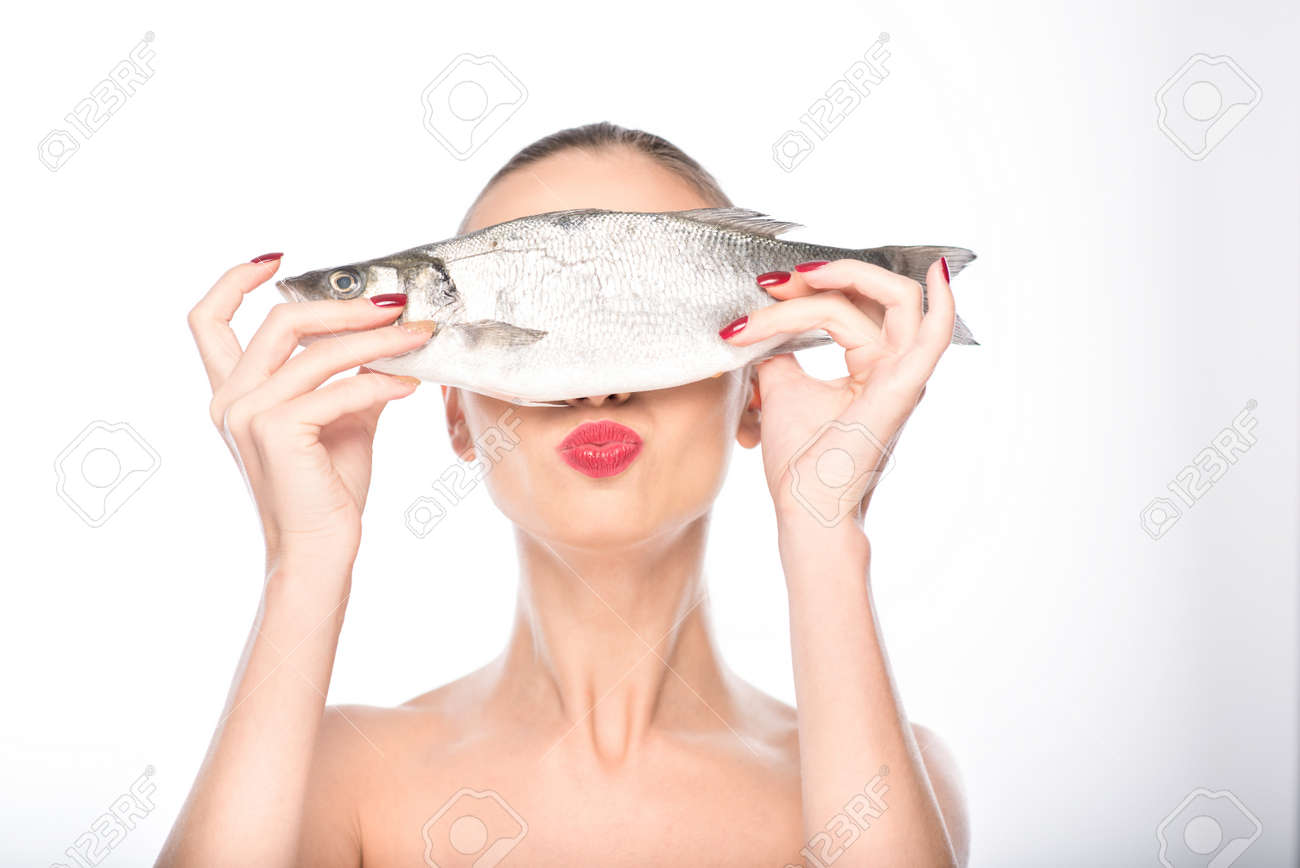 かわいい女の子は魚を保持 それで目を覆っています 彼女は 立っている カメラにキスを送信します 分離されました の写真素材 画像素材 Image