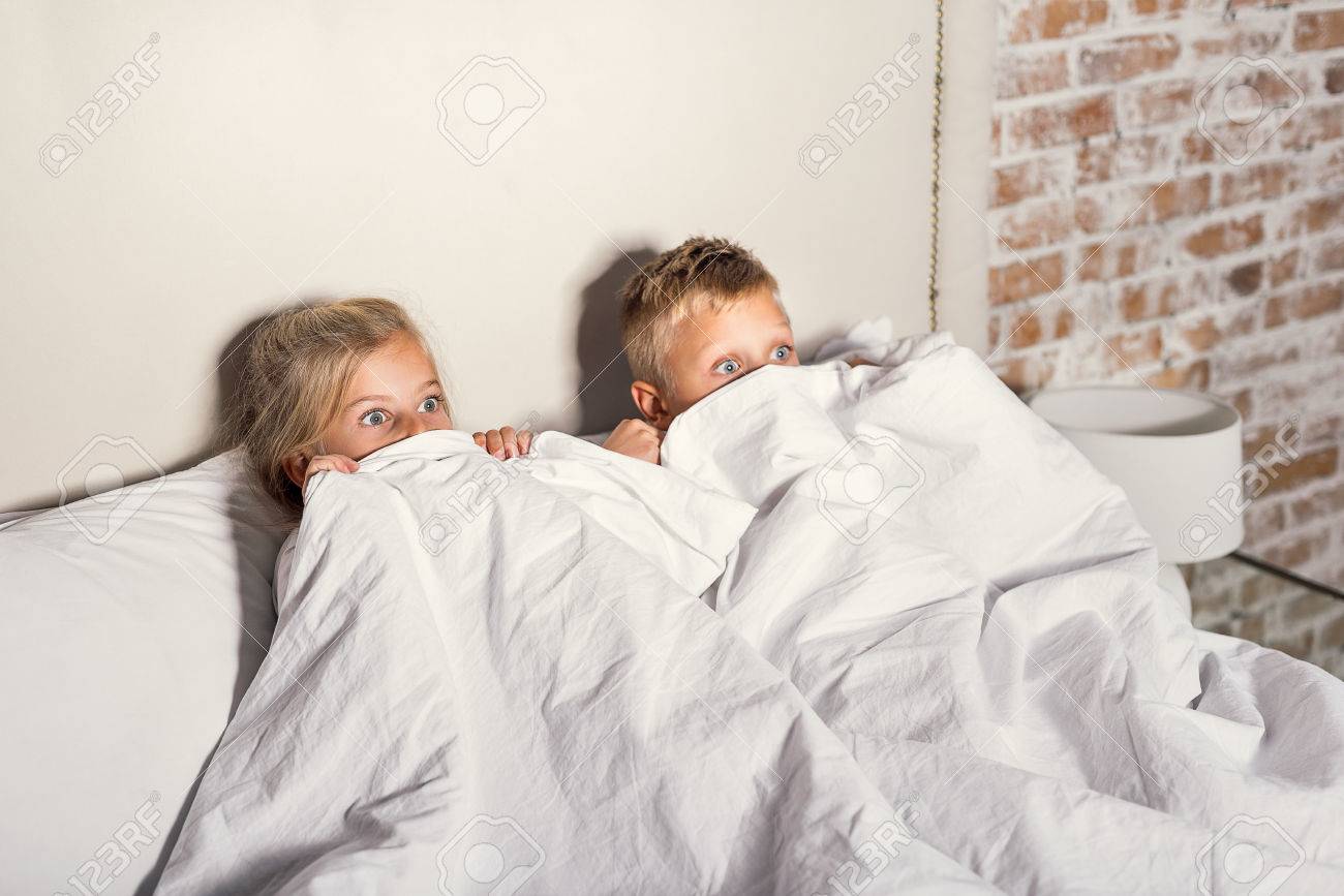 ホラー映画 ひどい話をテレビを見ながら白い毛布の後ろに隠れておびえている小さな子供たち の写真素材 画像素材 Image
