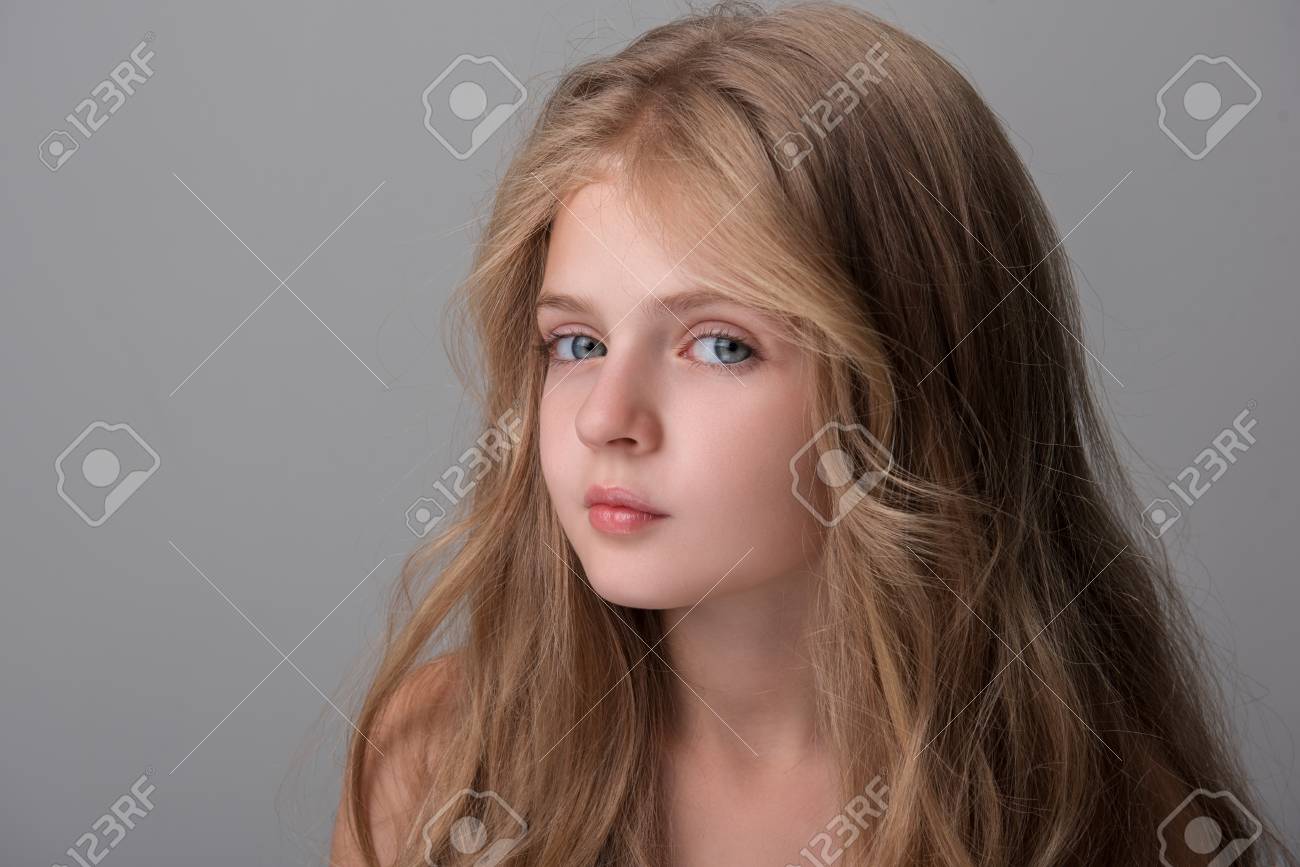 Interested Small Lovely Girl With Long Hair Is Looking At Camera