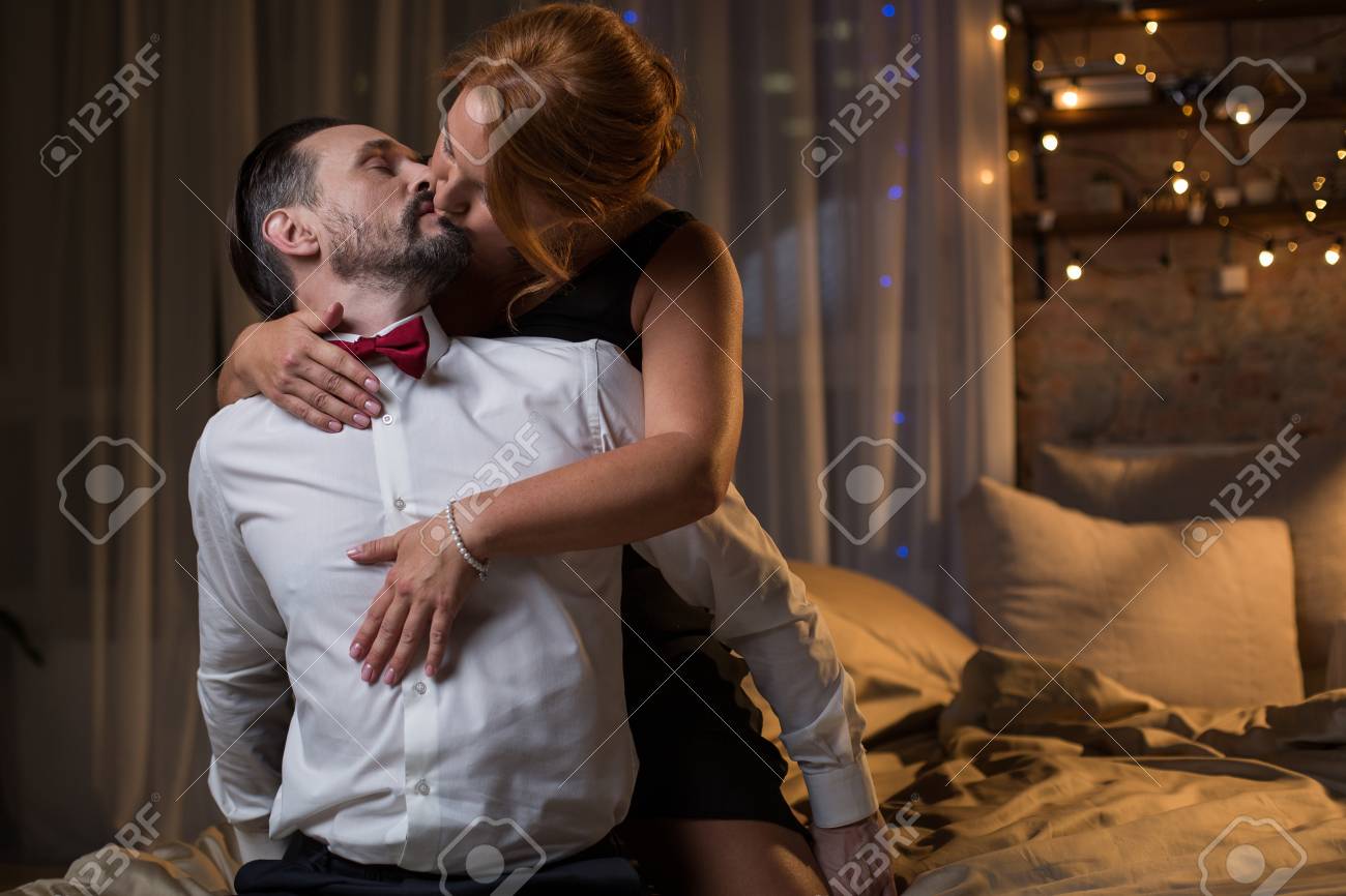 Passionate couple kissing intensely in bedroom