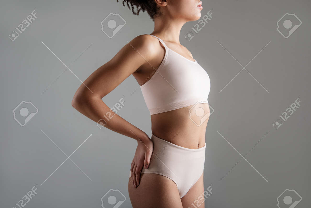 快適なランジェリーに立ち 彼女の腰に片手を保持して落ち着いた女性をフィット バックグラウンドで分離 の写真素材 画像素材 Image