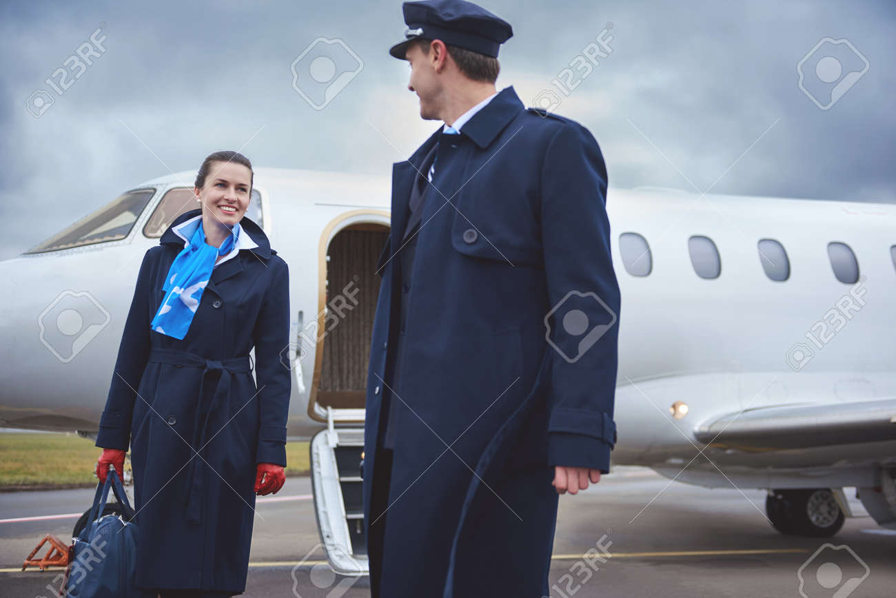 outgoing air hostess talking with happy pilot while going at stock hostess occupation