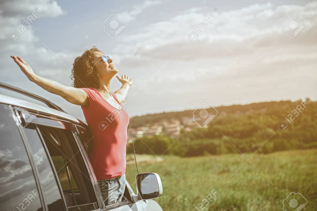This Is The Real Freedom. Excited Young Woman Is Enjoying Sunshine In The  Nature. She Is Stretching Arms Sideways While Standing Through Window In  The Car And Smiling. Copy Space Stock Photo,