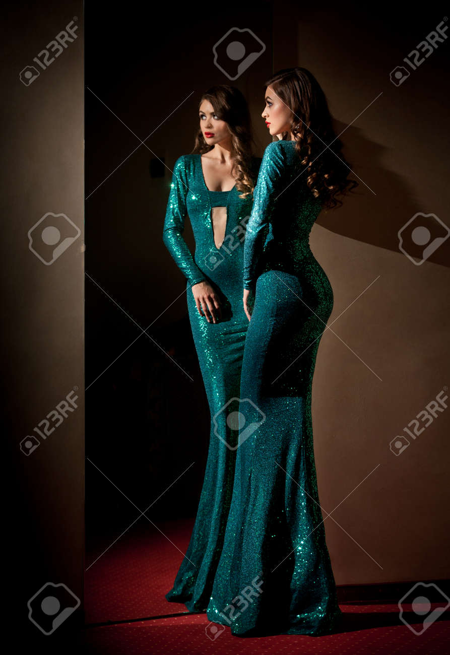 Elegant Young Woman In Turquoise Long Dress Looking Into A Large