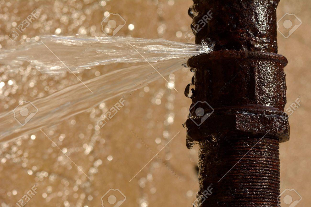 Rusty burst pipe spraying water. Old pipe leaking after freezing in winter - 63010371 Rusty burst pipe spraying water. Old pipe leaking after freezing in winter - 63010371