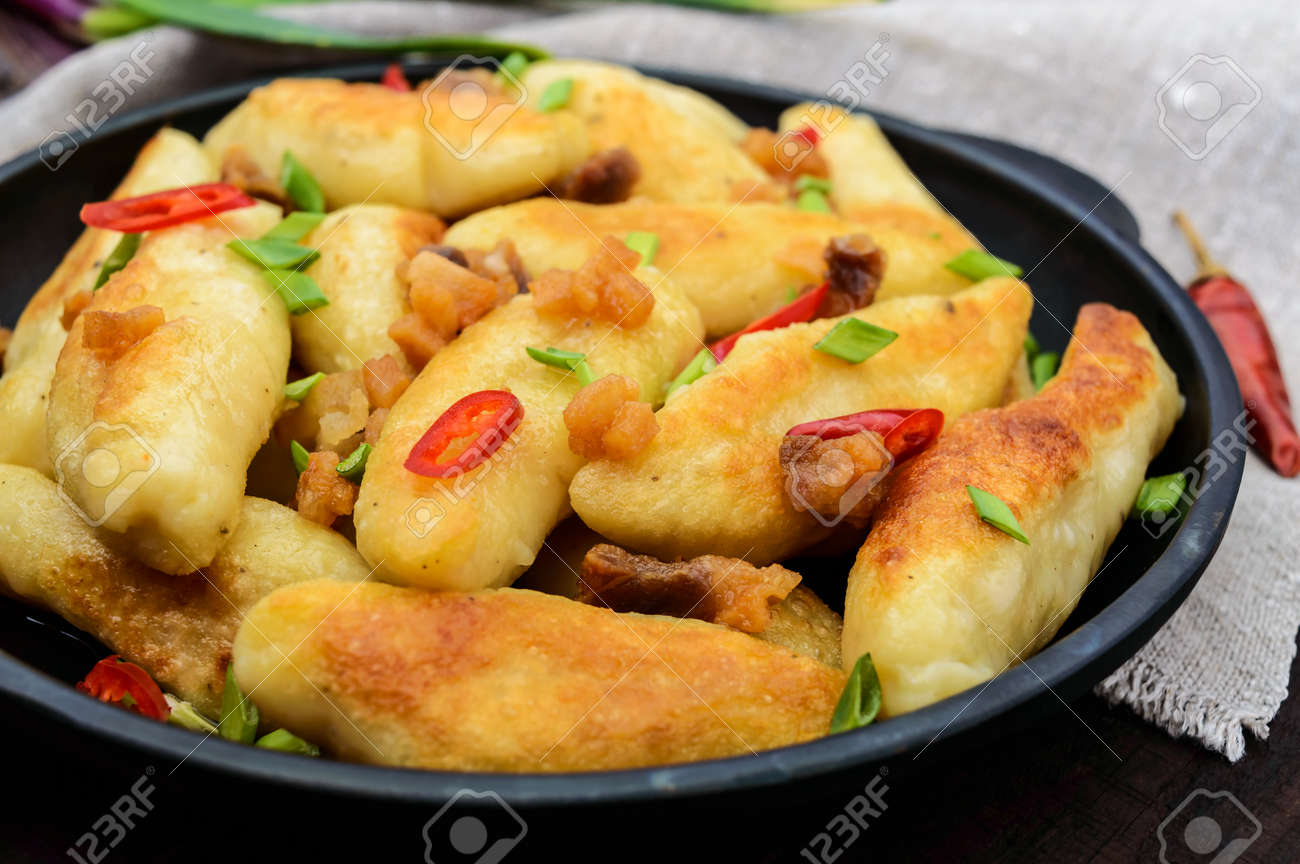 人気のある伝統的なチェコ語 ハンガリー語 ドイツ語の料理 ベーコン 赤唐辛子 ねぎのスライスとジャガイモの Knedli 餃子 鋳鉄鍋で料理 の写真素材 画像素材 Image