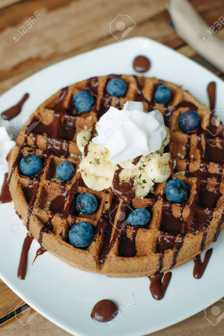Plate of belgian waffles with ice cream, chocolate sauce and fresh blueberries - 169729337 Plate of belgian waffles with ice cream, chocolate sauce and fresh blueberries - 169729337