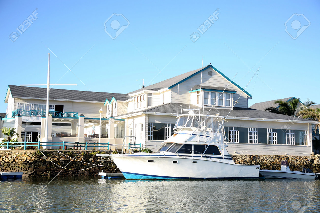 White Beach House a white beach house with a boat docked next to it stock photo White Beach House a white beach house with a boat docked next to it stock photo