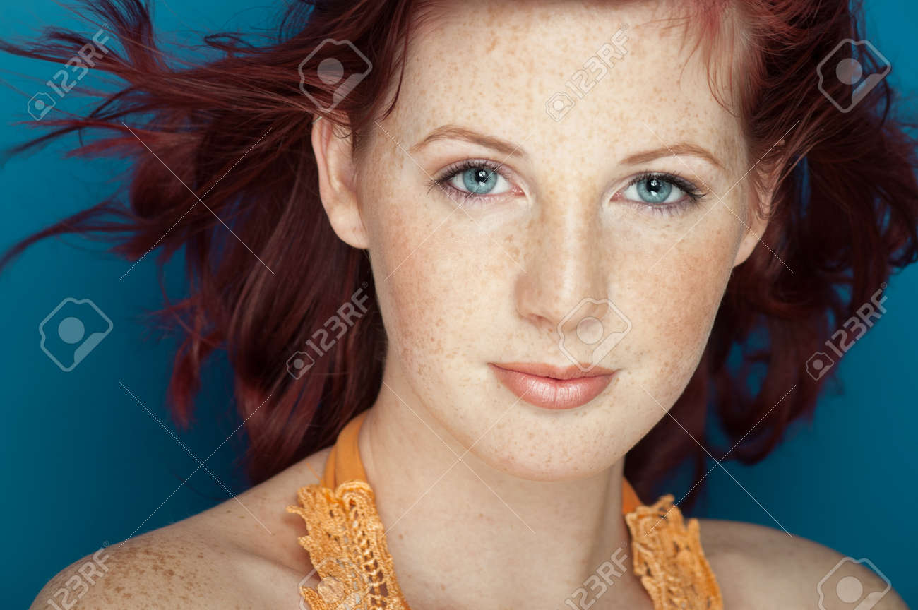 Beautiful fresh girl with auburn hair, blue eyes and freckles posing over blue background. - 38858942 Beautiful fresh girl with auburn hair, blue eyes and freckles posing over blue background. - 38858942