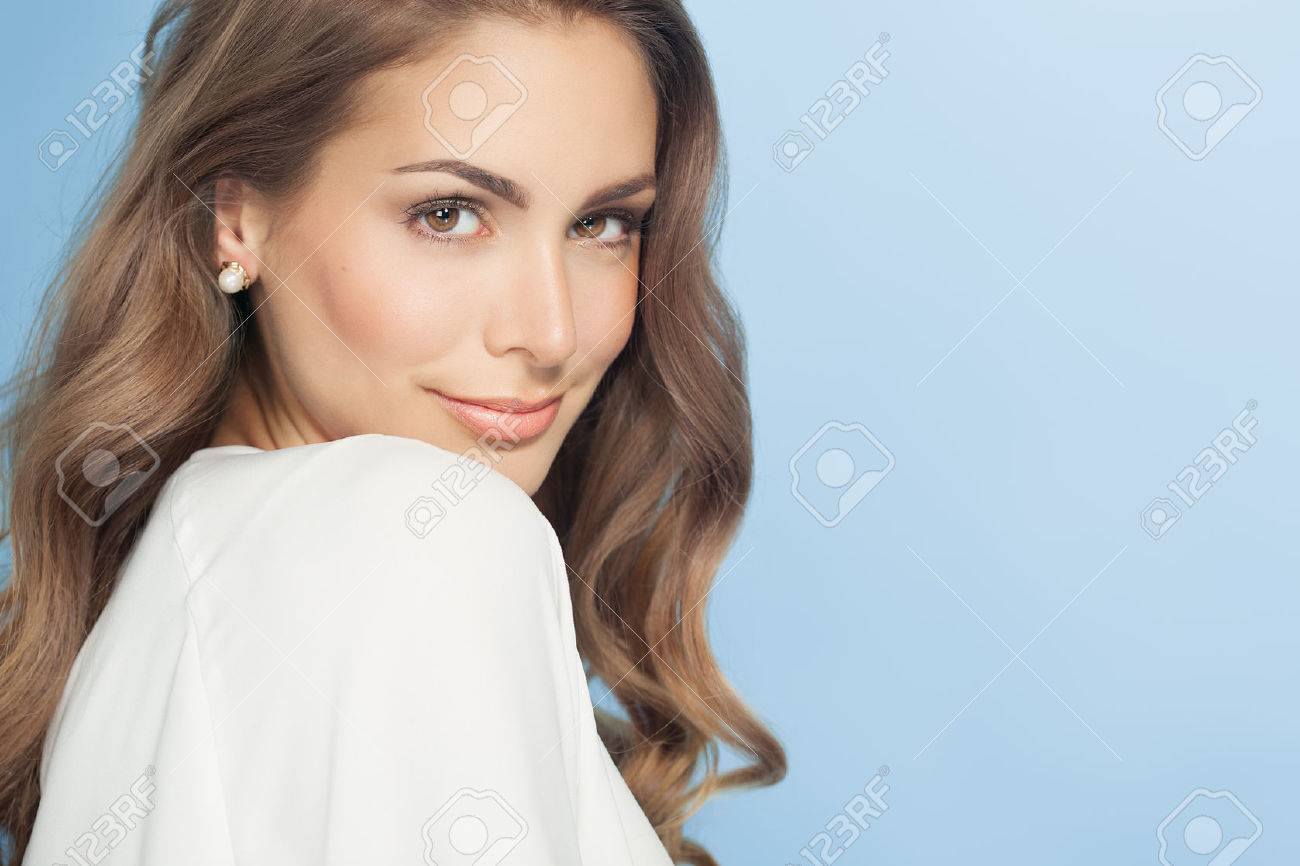 Young beautiful woman with long hair posing and smiling over blue background. Fashion and beauty concept in studio. - 51033458 Young beautiful woman with long hair posing and smiling over blue background. Fashion and beauty concept in studio. - 51033458